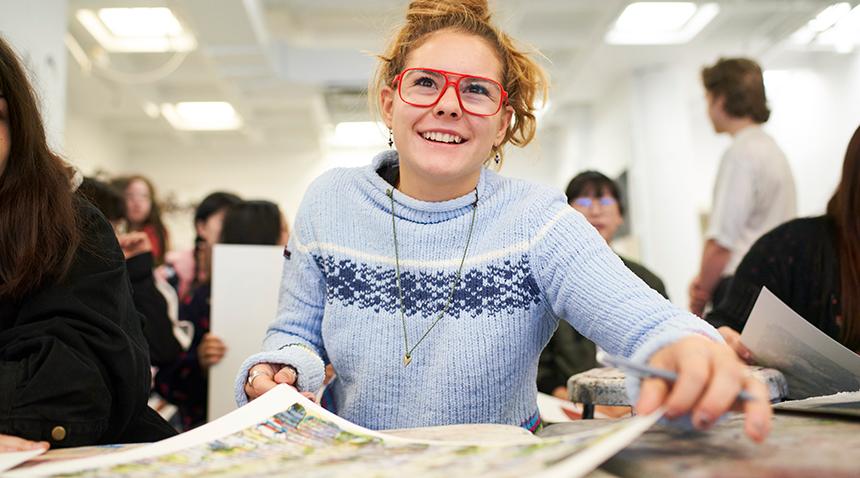 student smiling working on an art piece